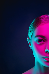 Image showing Portrait of female fashion model in neon light on dark studio background.