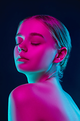 Image showing Portrait of female fashion model in neon light on dark studio background.