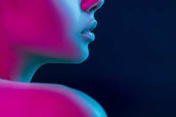 Image showing Close up portrait of female fashion model in neon light on dark studio background.