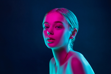 Image showing Portrait of female fashion model in neon light on dark studio background.