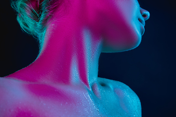 Image showing Close up portrait of female fashion model in neon light on dark studio background.