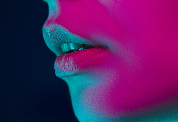 Image showing Close up portrait of female fashion model in neon light on dark studio background.