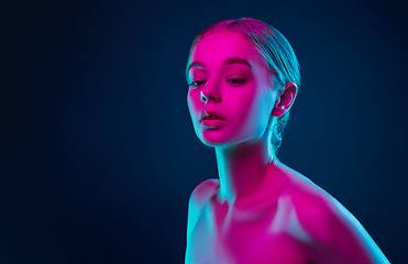 Image showing Portrait of female fashion model in neon light on dark studio background.