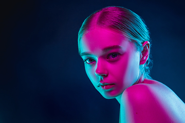 Image showing Portrait of female fashion model in neon light on dark studio background.