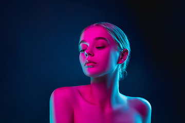 Image showing Portrait of female fashion model in neon light on dark studio background.