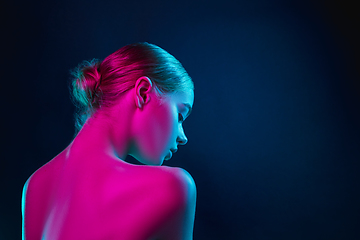 Image showing Portrait of female fashion model in neon light on dark studio background.