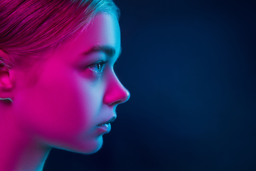 Image showing Portrait of female fashion model in neon light on dark studio background.