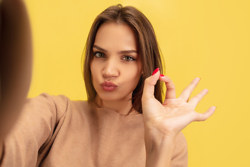 Image showing Portrait of young caucasian woman with bright emotions isolated on yellow studio background