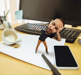 Image showing Tired man, office worker holding his huge tired head, funny