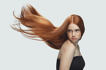 Image showing Beautiful model with long smooth, flying red hair isolated on white studio background.