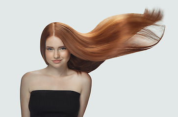 Image showing Beautiful model with long smooth, flying red hair isolated on white studio background.