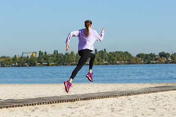 Image showing Young woman training outdoors in autumn sunshine. Concept of sport, healthy lifestyle, movement, activity.