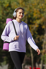 Image showing Young woman training outdoors in autumn sunshine. Concept of sport, healthy lifestyle, movement, activity.