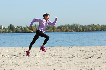 Image showing Young woman training outdoors in autumn sunshine. Concept of sport, healthy lifestyle, movement, activity.