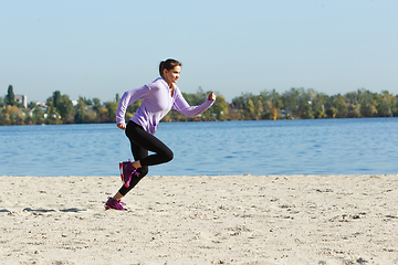 Image showing Young woman training outdoors in autumn sunshine. Concept of sport, healthy lifestyle, movement, activity.