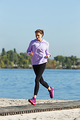 Image showing Young woman training outdoors in autumn sunshine. Concept of sport, healthy lifestyle, movement, activity.