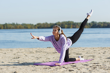 Image showing Young woman training outdoors in autumn sunshine. Concept of sport, healthy lifestyle, movement, activity.