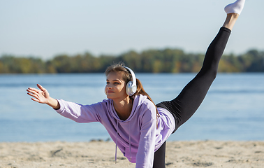 Image showing Young woman training outdoors in autumn sunshine. Concept of sport, healthy lifestyle, movement, activity.