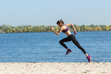 Image showing Young woman training outdoors in autumn sunshine. Concept of sport, healthy lifestyle, movement, activity.