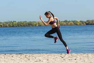 Image showing Young woman training outdoors in autumn sunshine. Concept of sport, healthy lifestyle, movement, activity.