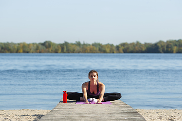 Image showing Young woman training outdoors in autumn sunshine. Concept of sport, healthy lifestyle, movement, activity.