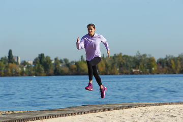 Image showing Young woman training outdoors in autumn sunshine. Concept of sport, healthy lifestyle, movement, activity.