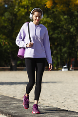 Image showing Young woman training outdoors in autumn sunshine. Concept of sport, healthy lifestyle, movement, activity.