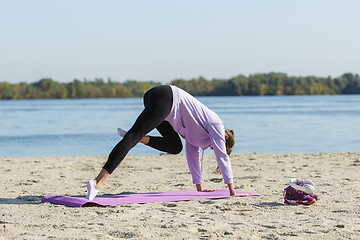 Image showing Young woman training outdoors in autumn sunshine. Concept of sport, healthy lifestyle, movement, activity.