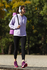 Image showing Young woman training outdoors in autumn sunshine. Concept of sport, healthy lifestyle, movement, activity.