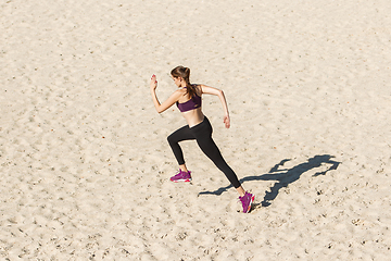 Image showing Young woman training outdoors in autumn sunshine. Concept of sport, healthy lifestyle, movement, activity.