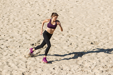 Image showing Young woman training outdoors in autumn sunshine. Concept of sport, healthy lifestyle, movement, activity.