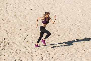 Image showing Young woman training outdoors in autumn sunshine. Concept of sport, healthy lifestyle, movement, activity.