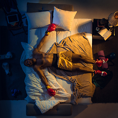 Image showing Top view of young professional boxer, fighter sleeping at his bedroom in sportwear with gloves