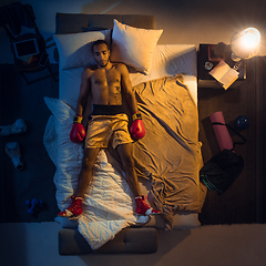 Image showing Top view of young professional boxer, fighter sleeping at his bedroom in sportwear with gloves