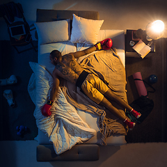 Image showing Top view of young professional boxer, fighter sleeping at his bedroom in sportwear with gloves