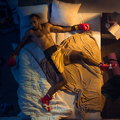 Image showing Top view of young professional boxer, fighter sleeping at his bedroom in sportwear with gloves
