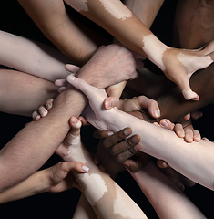 Image showing Hands of different people in touch isolated on black studio background. Concept of human relation, community, togetherness, inclusion