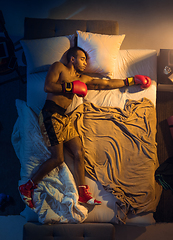 Image showing Top view of young professional boxer, fighter sleeping at his bedroom in sportwear with gloves