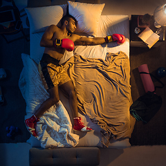 Image showing Top view of young professional boxer, fighter sleeping at his bedroom in sportwear with gloves