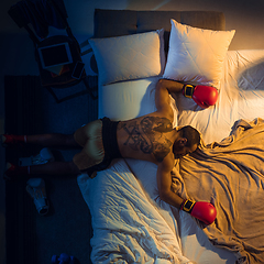 Image showing Top view of young professional boxer, fighter sleeping at his bedroom in sportwear with gloves