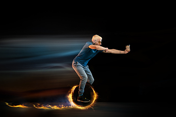 Image showing Fast delivery service - deliveryman on unicycle driving with order in fire on dark background