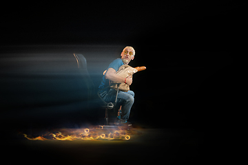 Image showing Fast delivery service - deliveryman on chair driving with order in fire on dark background