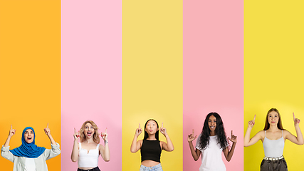 Image showing Young people pointing up smiling on multicolored background. Human emotions, facial expression concept. Trendy colors. Creative collage.