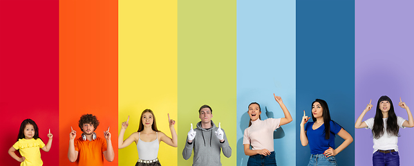 Image showing Young people pointing up smiling on multicolored background. Human emotions, facial expression concept. Trendy colors. Creative collage.