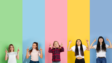 Image showing Young people pointing up smiling on multicolored background. Human emotions, facial expression concept. Trendy colors. Creative collage.