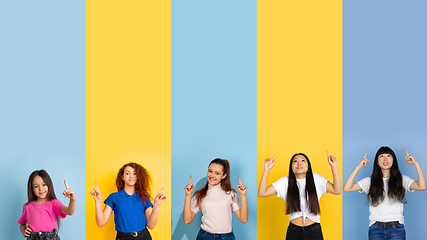 Image showing Young people pointing up smiling on multicolored background. Human emotions, facial expression concept. Trendy colors. Creative collage.
