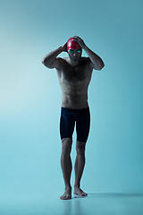 Image showing Professional male swimmer with hat and goggles in motion and action, healthy lifestyle and movement concept. Neoned style.