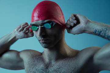 Image showing Professional male swimmer with hat and goggles in motion and action, healthy lifestyle and movement concept. Neoned style.