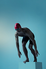 Image showing Professional male swimmer with hat and goggles in motion and action, healthy lifestyle and movement concept. Neoned style.