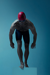 Image showing Professional male swimmer with hat and goggles in motion and action, healthy lifestyle and movement concept. Neoned style.